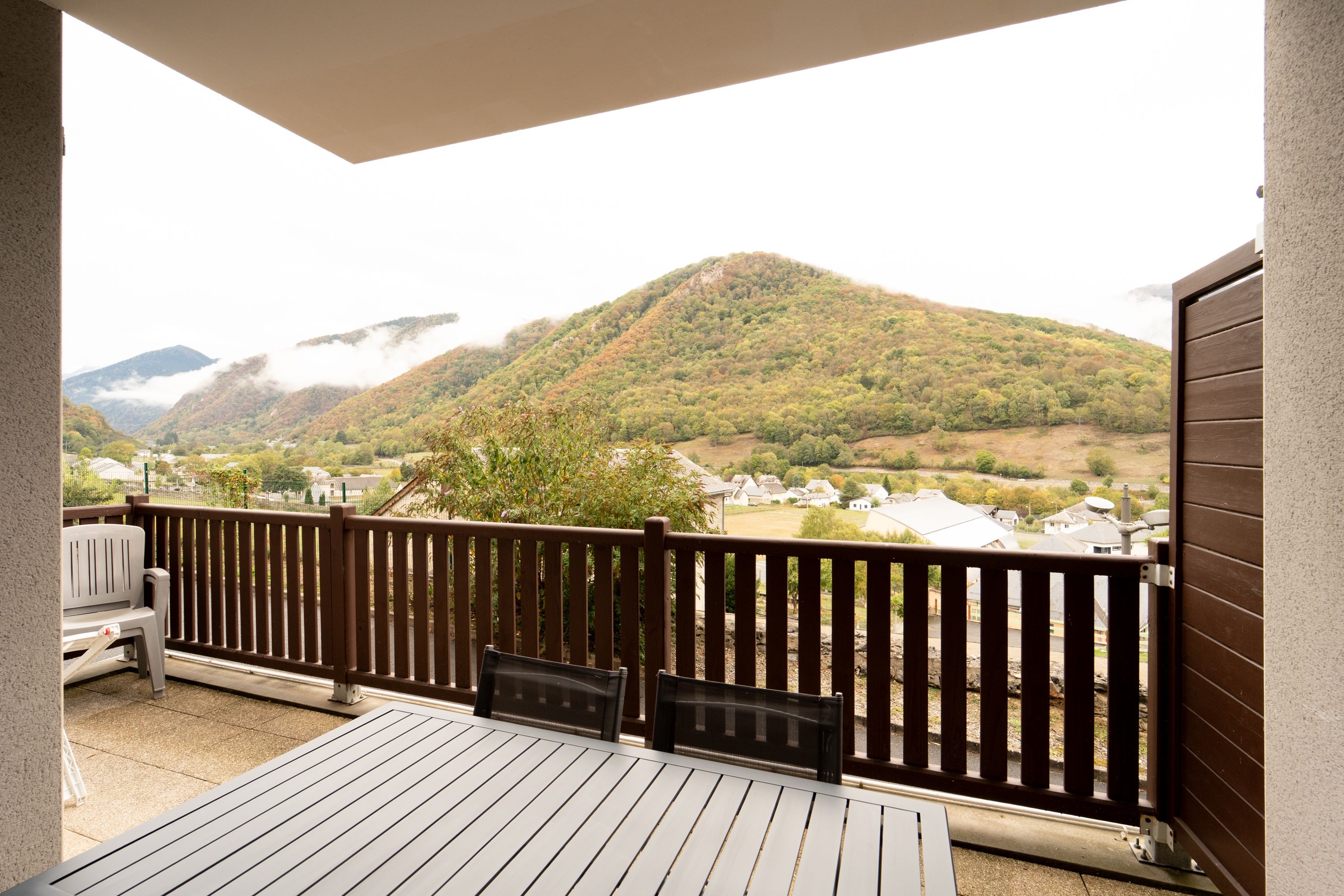 Un balcon donnant sur un paysage vallonné et sur un village situé en contrebas.