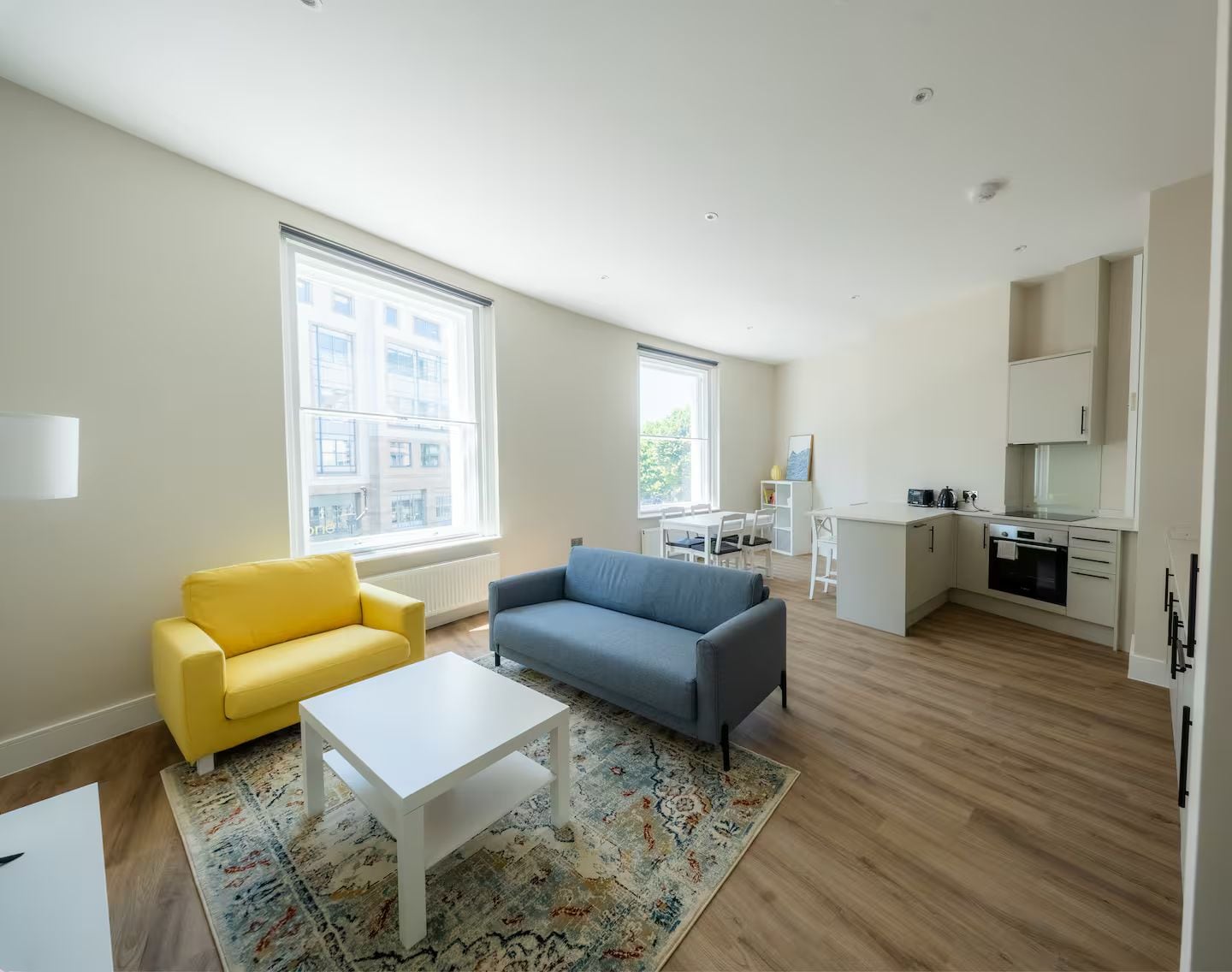 A modern living room with a sofa, a coffee table, and a kitchen area with cabinets and appliances.