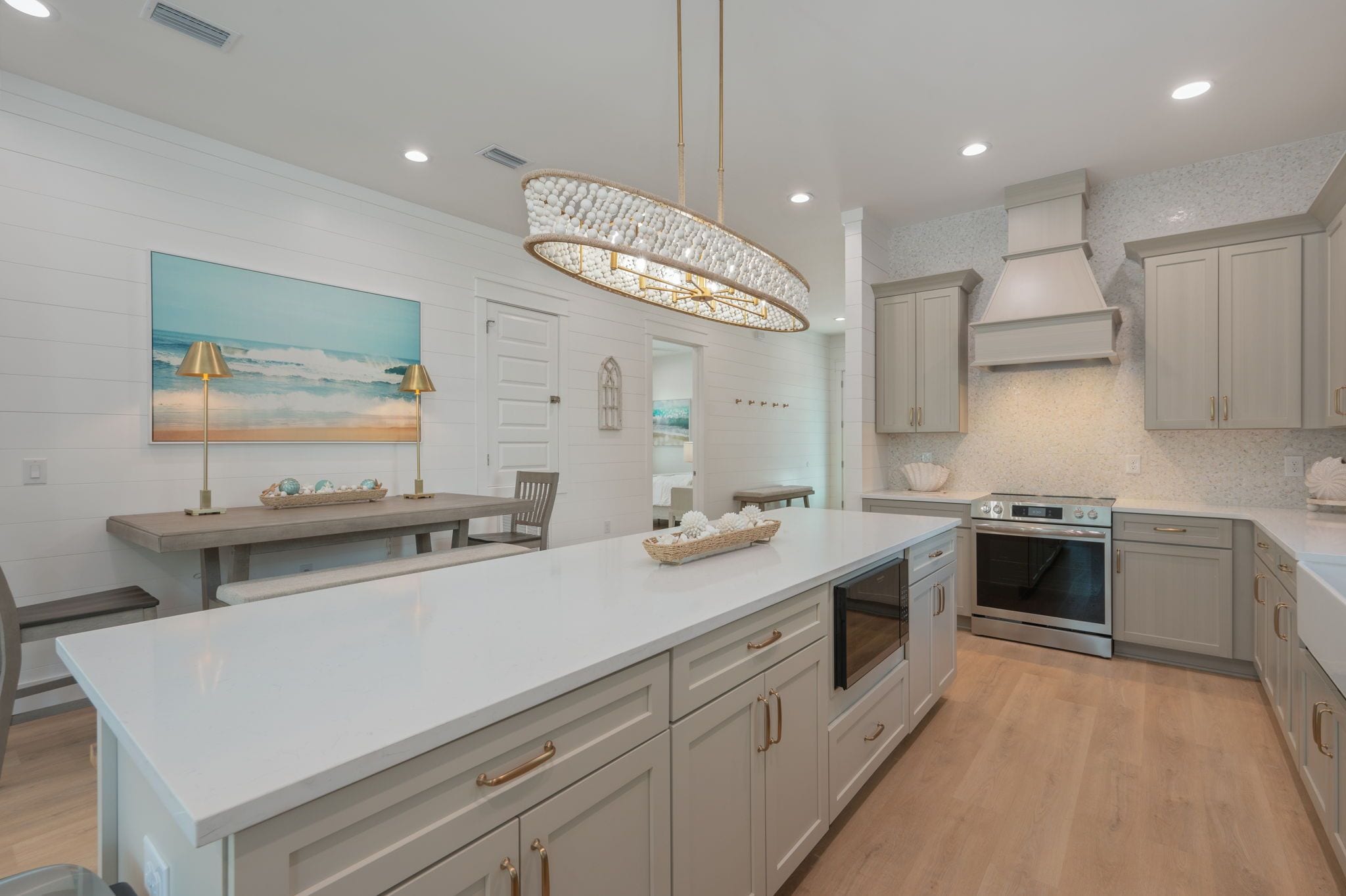 A modern kitchen with a central island, built-in appliances, and a coastal-themed artwork.