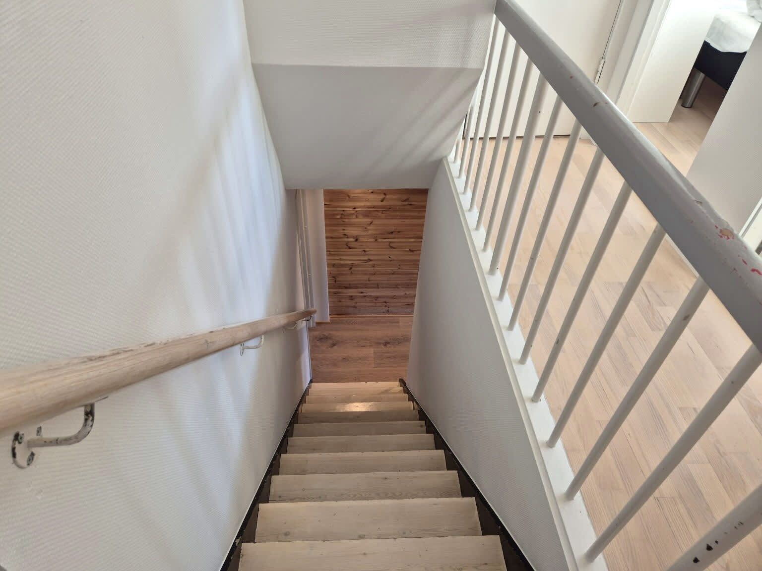 A staircase with wooden steps and white walls, leading to a lower level.