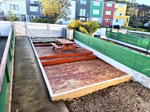 Eine Dachterrasse mit Picknicktisch und Treppe zu einem Gartenbereich.