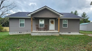 A two-story house with a front porch, two windows on the ground floor, and a door with a wreath.
