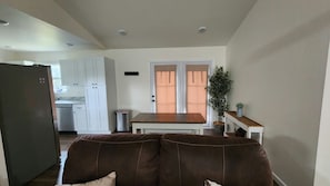 A living room with a brown leather sofa, a dining table, and a kitchen in the background.