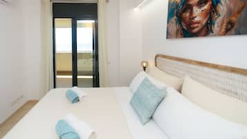 Une chambre d’hôtel avec un lit, une table de chevet, un tableau au mur et une vue sur l’extérieur, visible à travers une porte.