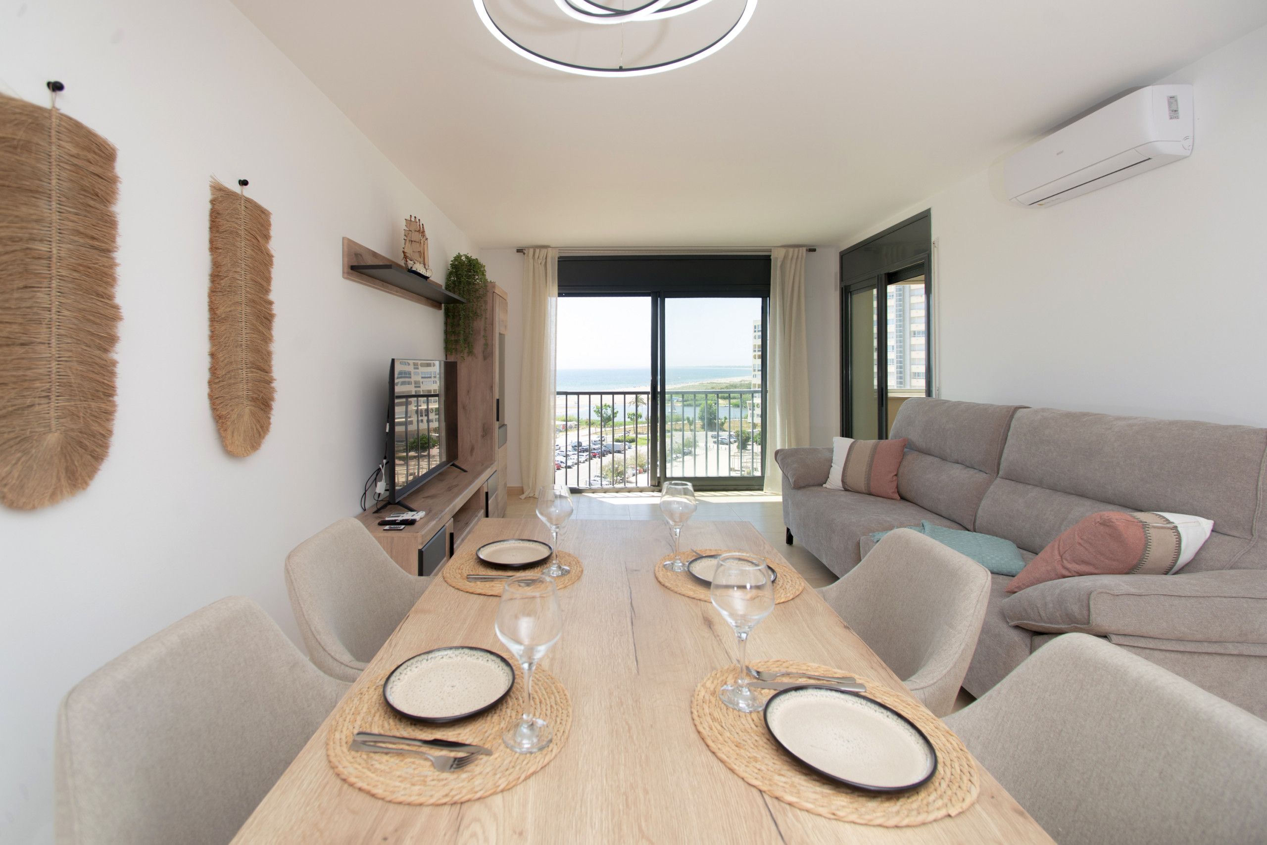 A modern living room with a dining table set for two, a sofa, and a television.