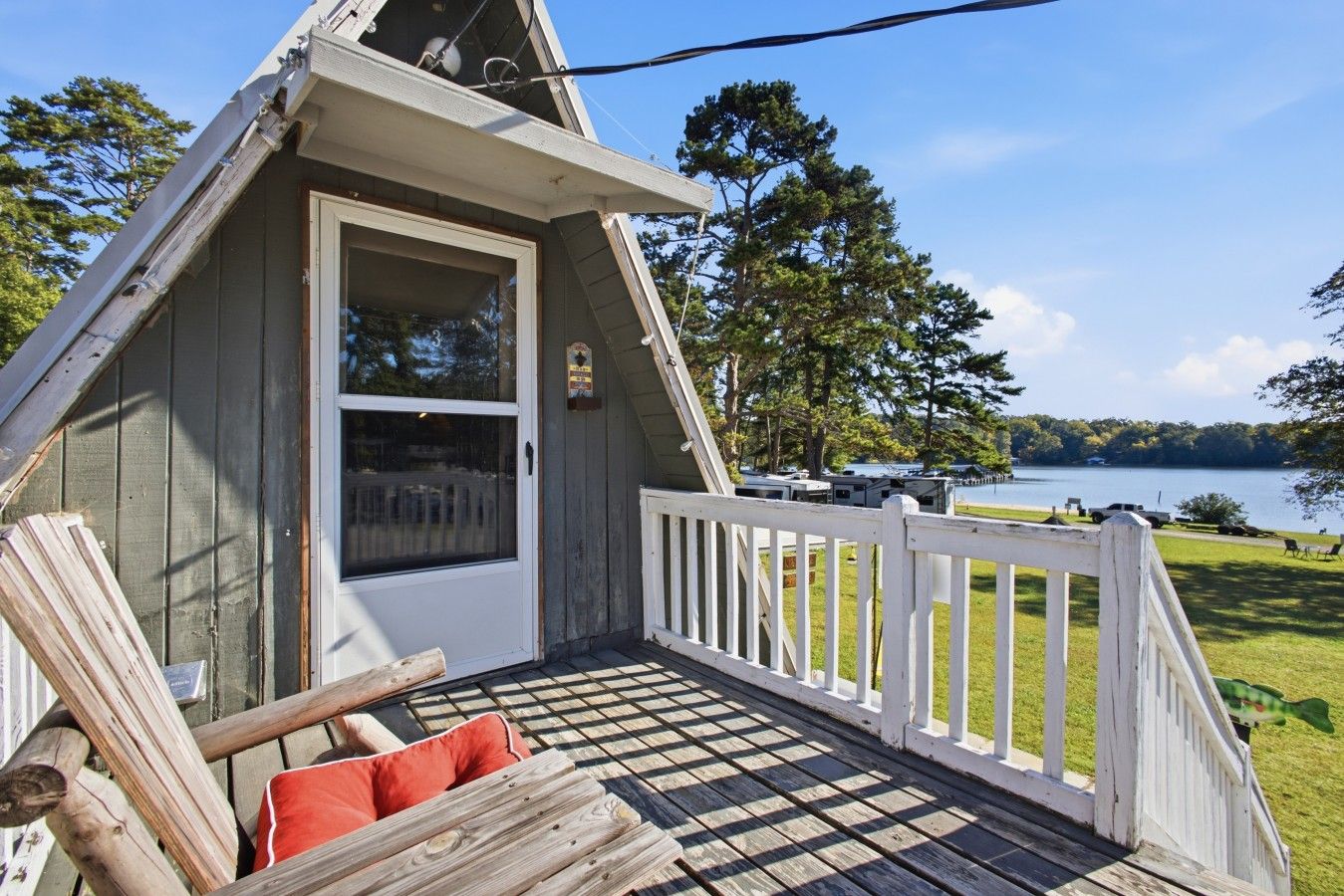 A small, single-story cabin with a porch and a view of a lake.