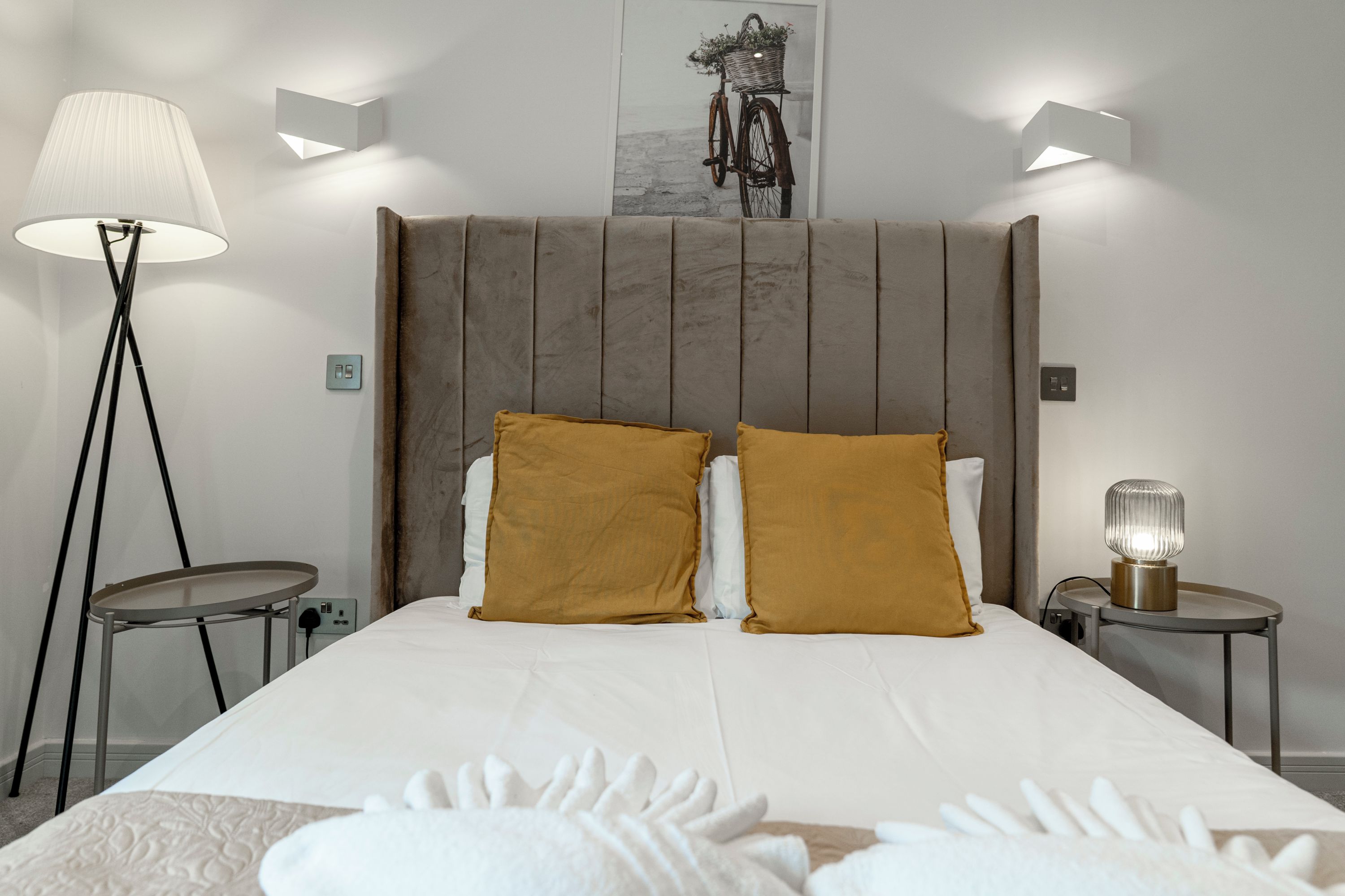 Ett hotellrum med en stor säng, två sängbord, en golvlampa och en väggmonterad lampa.