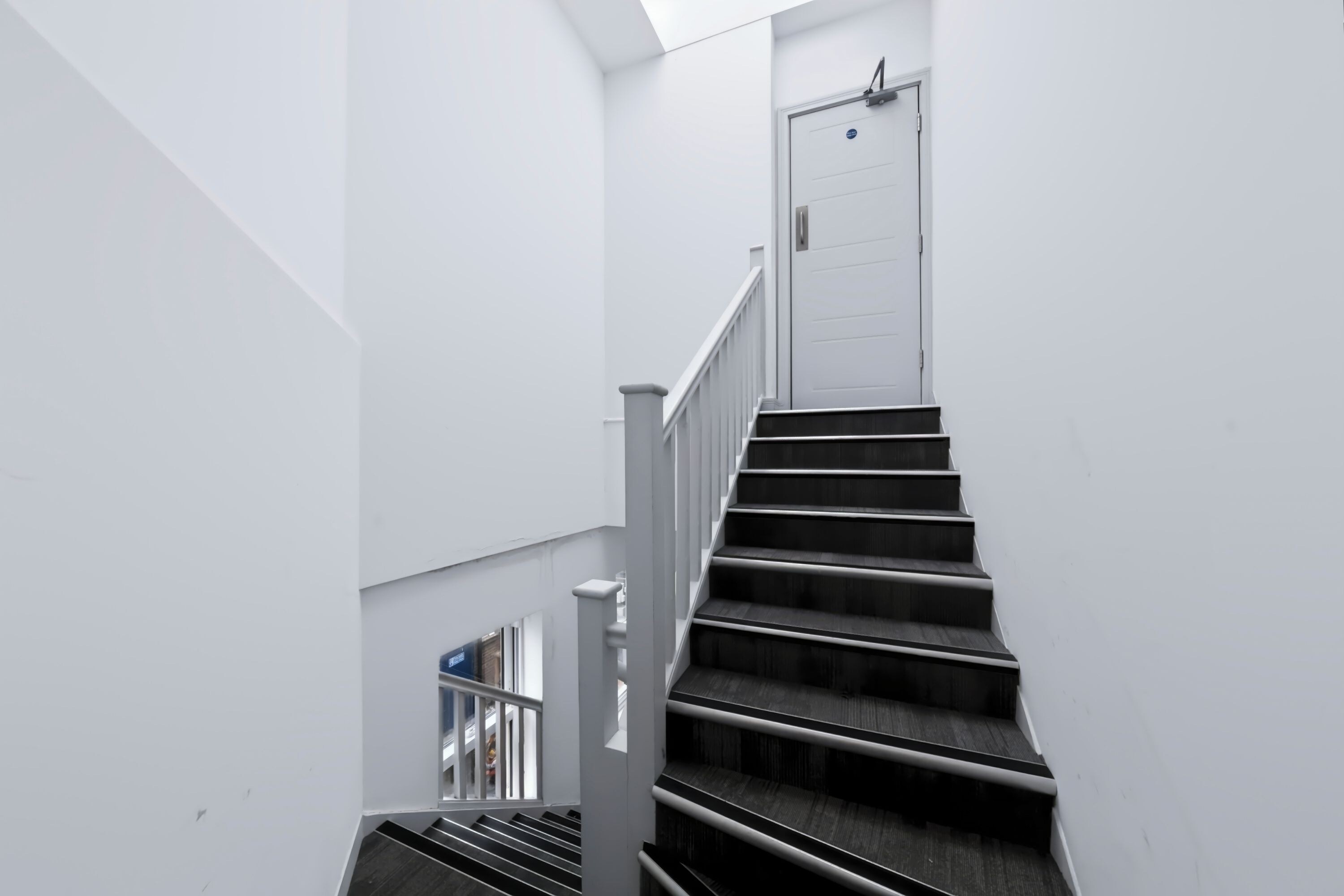 A staircase with a white door at the top, leading to an upper floor.