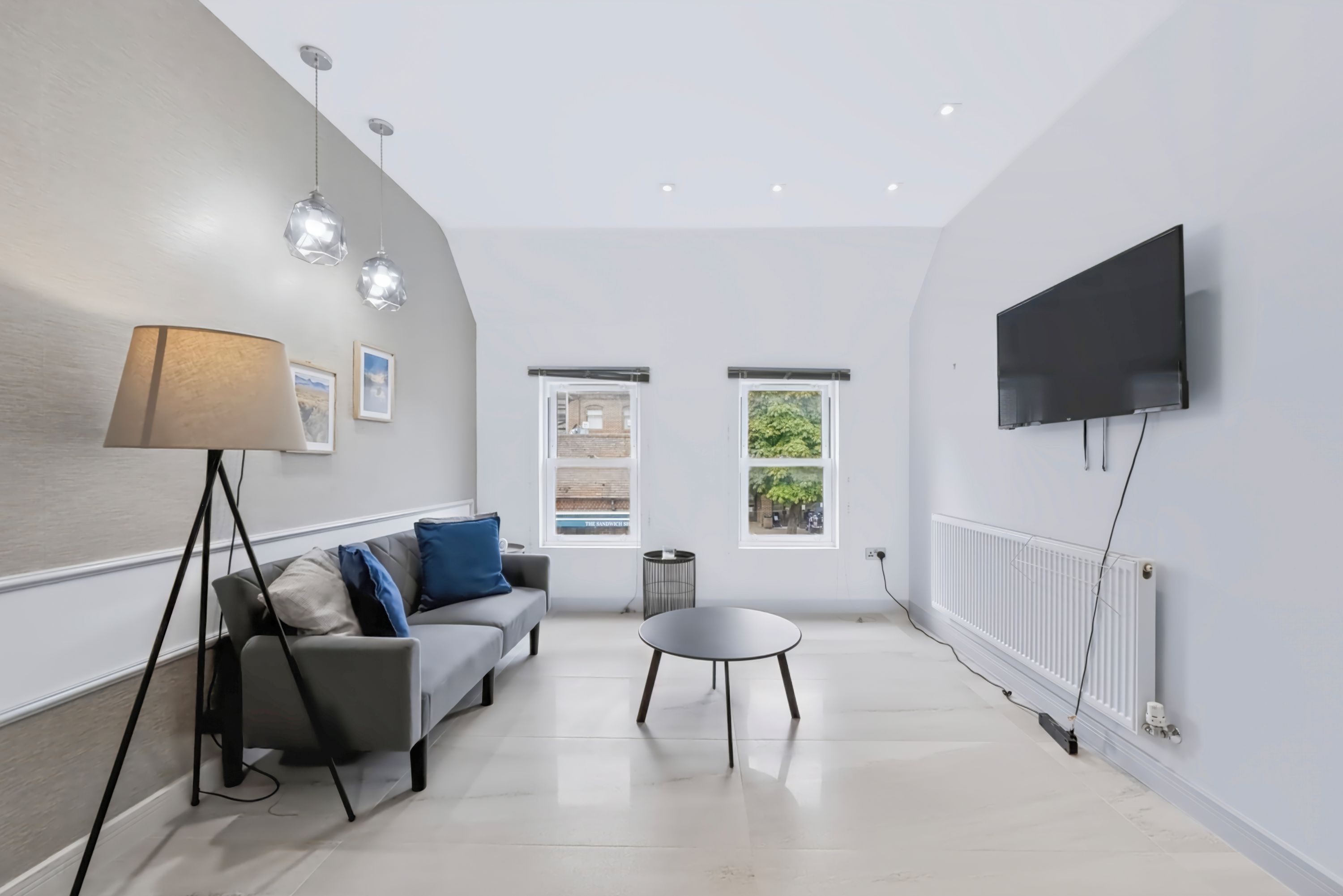 A modern living room with a sofa, a coffee table, and a TV mounted on the wall.