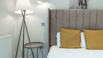 Ein Schlafzimmer mit einem Bett, einem Nachttisch, einer Stehlampe und einer Wandleuchte.
