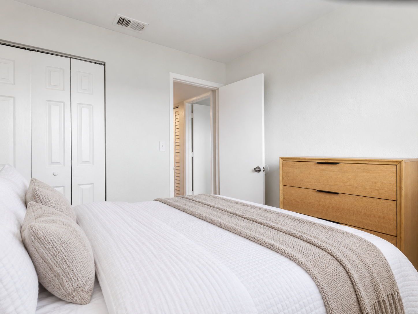 Ein Schlafzimmer mit einem Bett, einer Holzkommode und einem Kleiderschrank.