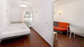 A compact room with a bed, a small table, and a sofa.