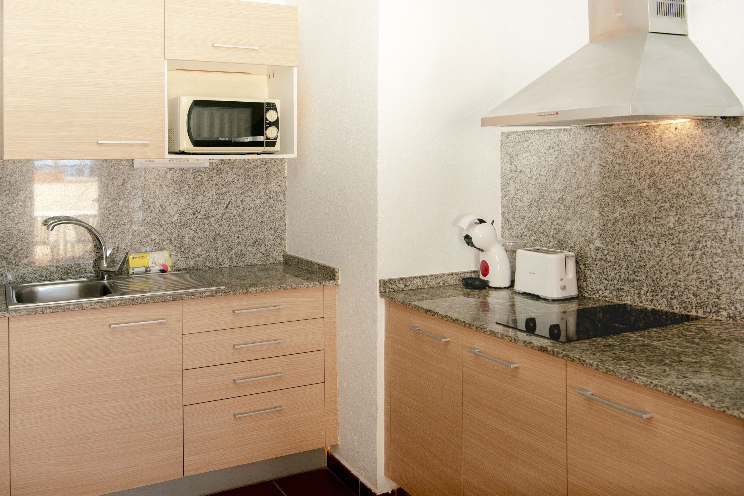 A kitchen with a microwave, toaster, and sink.