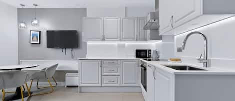 A modern kitchen with white cabinetry, a built-in oven, a microwave, and a stainless steel sink.