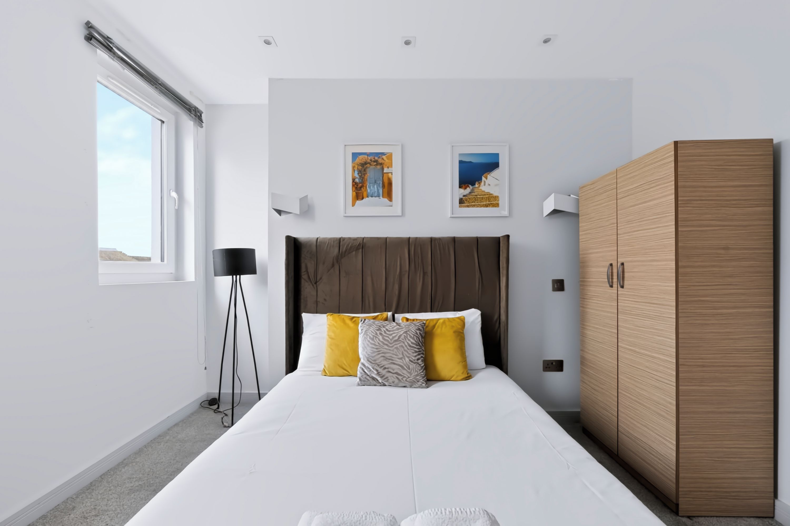 Ein modernes Schlafzimmer mit einem großen Bett, einem Kleiderschrank und zwei gerahmten Bildern an der Wand.