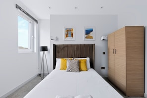 Une chambre moderne avec un grand lit, une armoire et deux tableaux encadrés accrochés au mur.