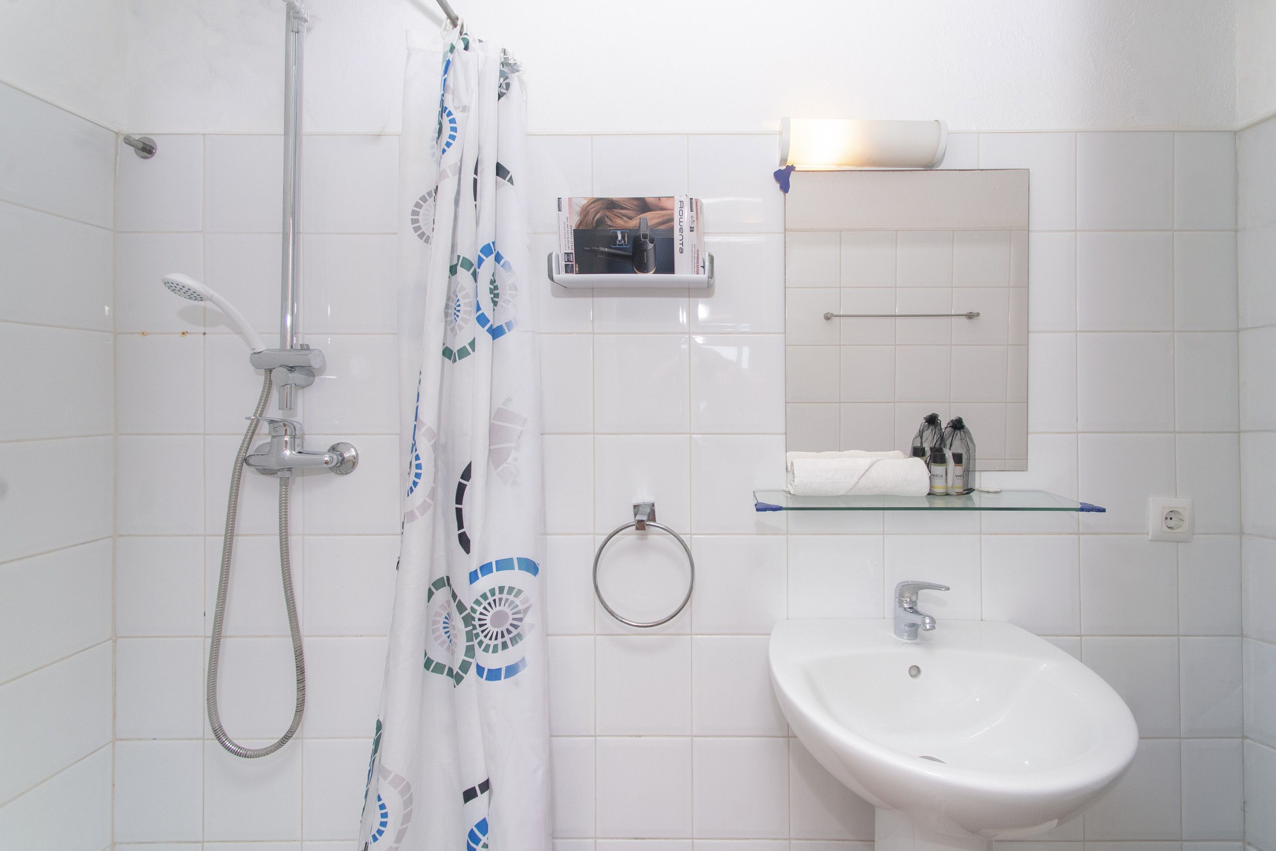 Un baño con ducha, lavabo, toallero y espejo.