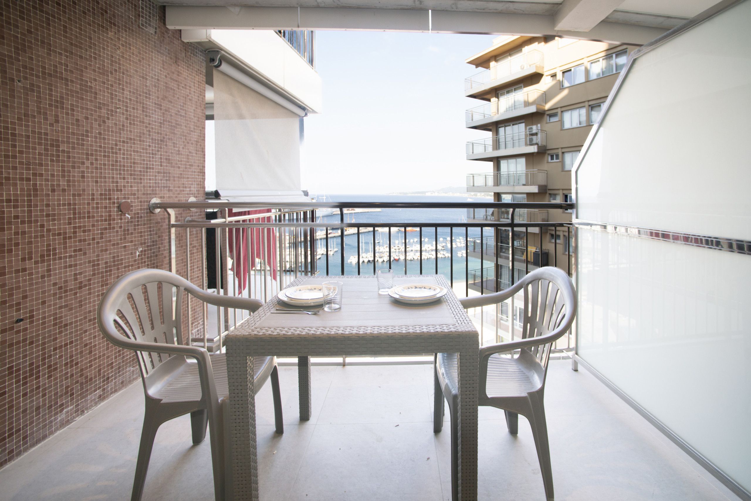 A balcony with a table and chairs, overlooking a marina with boats.