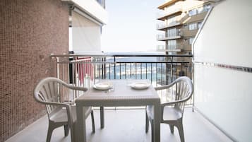 A balcony with a table and chairs, overlooking a marina with boats.