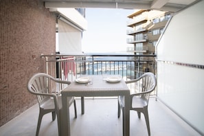 Varanda com mesa e cadeiras, com vista para uma marina e barcos.