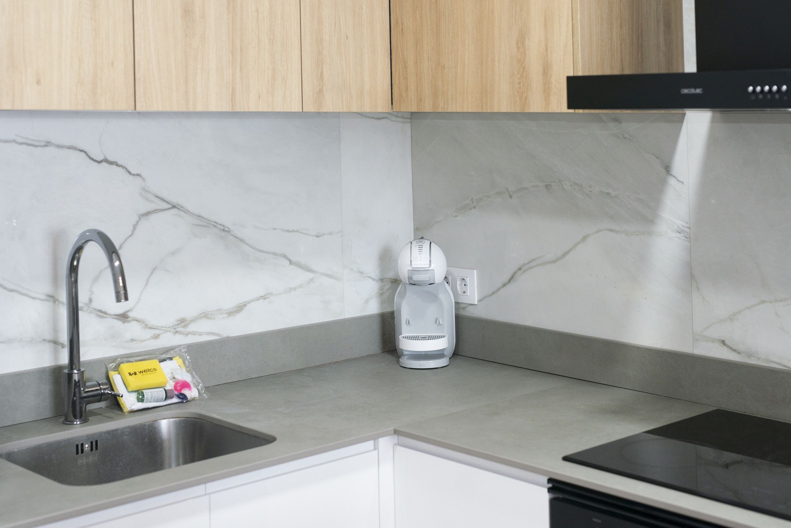 A kitchen with a sink, a coffee maker, and a bag of coffee pods.