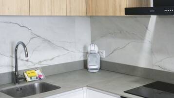 A kitchen with a sink, a coffee maker, and a bag of coffee pods.