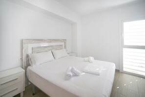 Quarto de hotel com cama, mesa de cabeceira, janela e vista exterior.