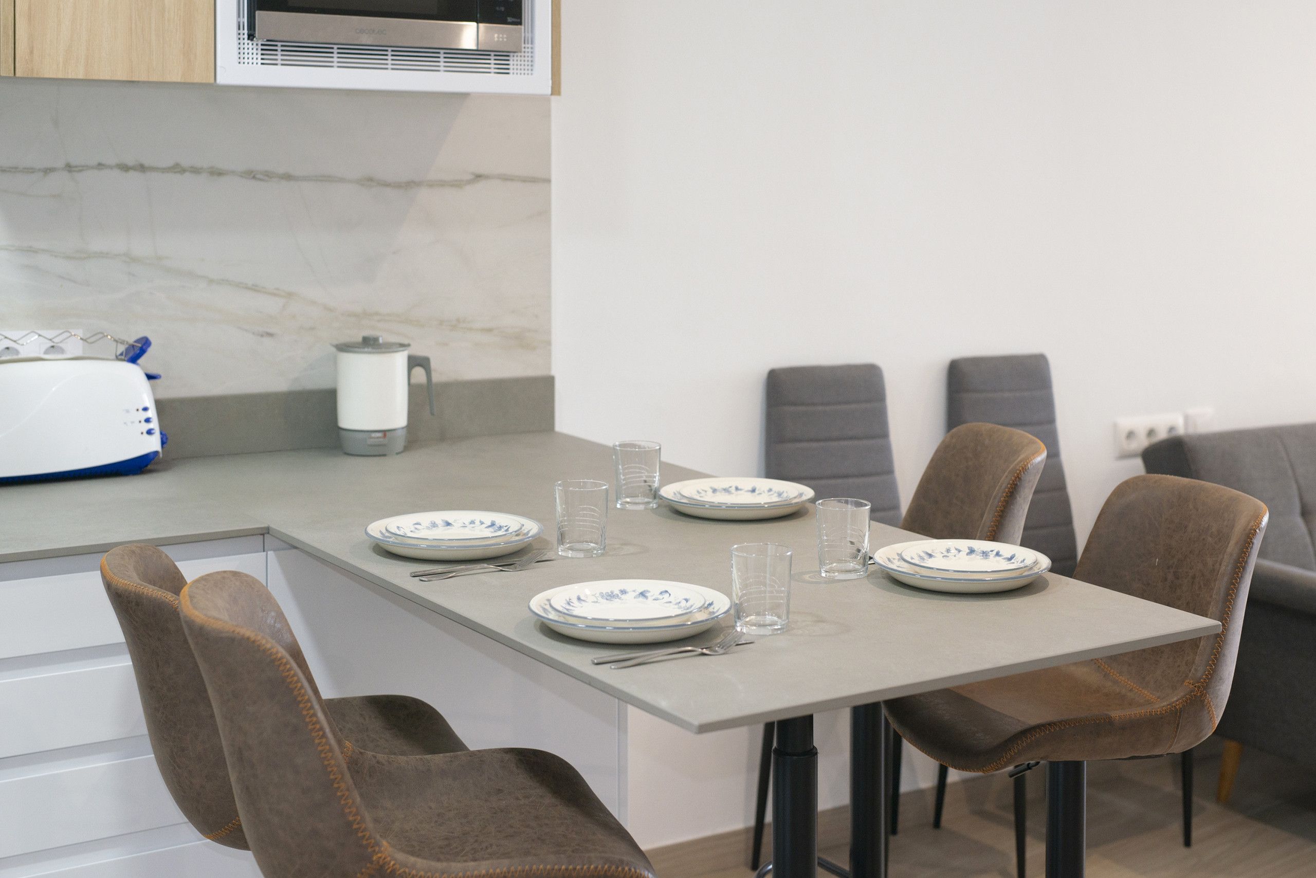Comedor con una mesa dispuesta para cuatro personas, incluyendo platos, vasos y cubiertos.