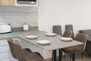 Un coin repas avec une table dressée pour quatre personnes, comprenant des assiettes, des verres et des couverts.