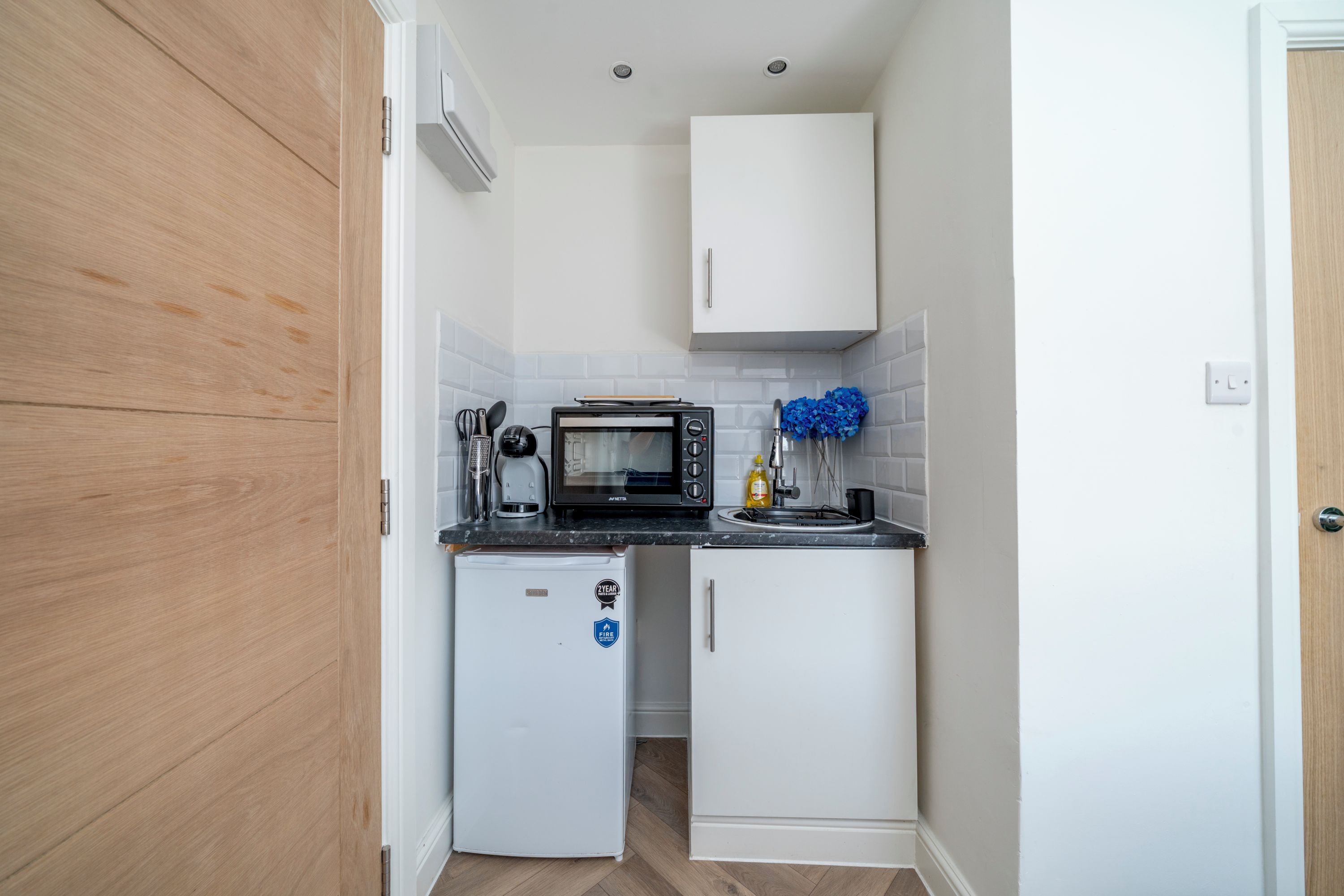A compact kitchen with a microwave, coffee maker, and a small refrigerator.