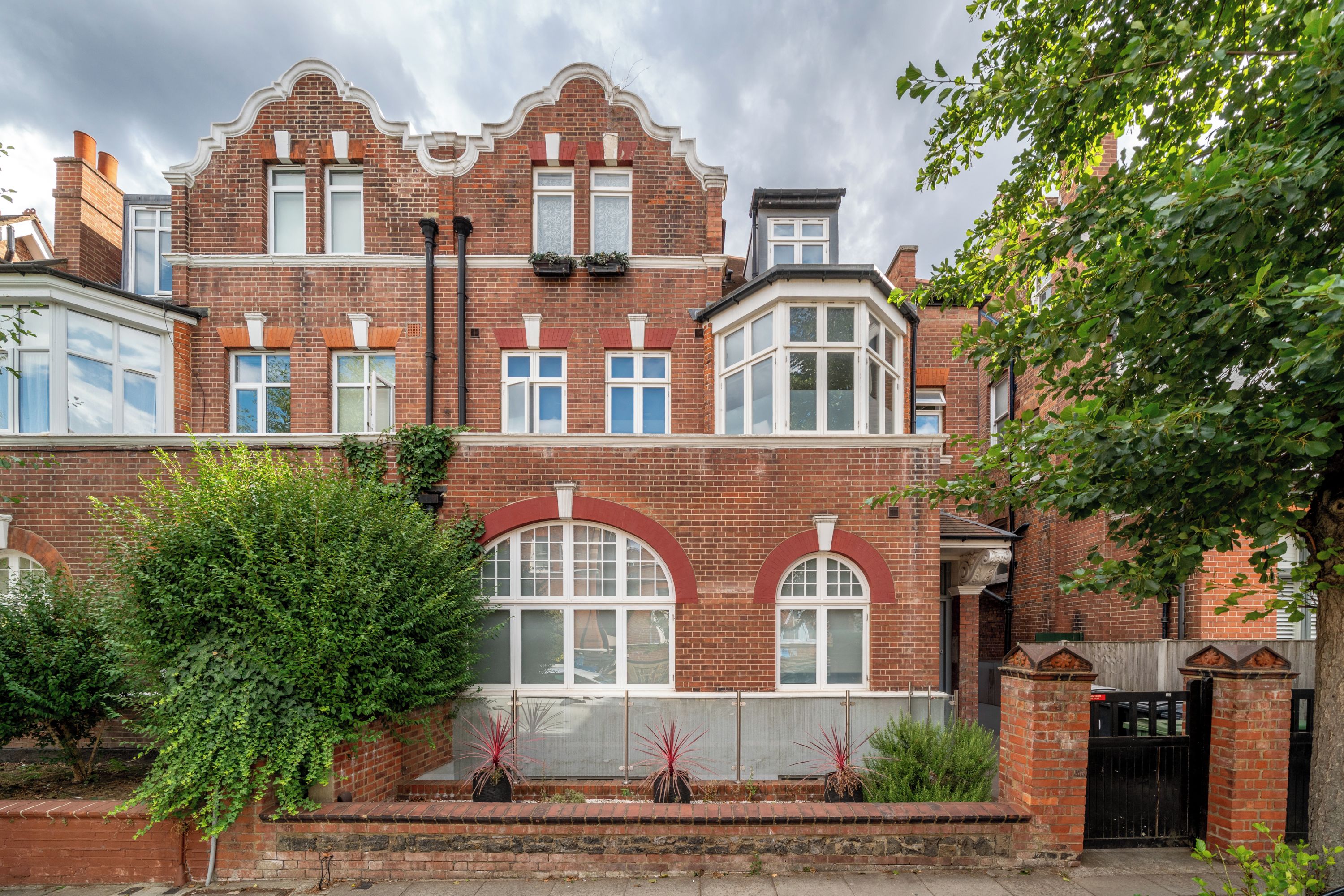A two-story brick building with a bay window and a conservatory.