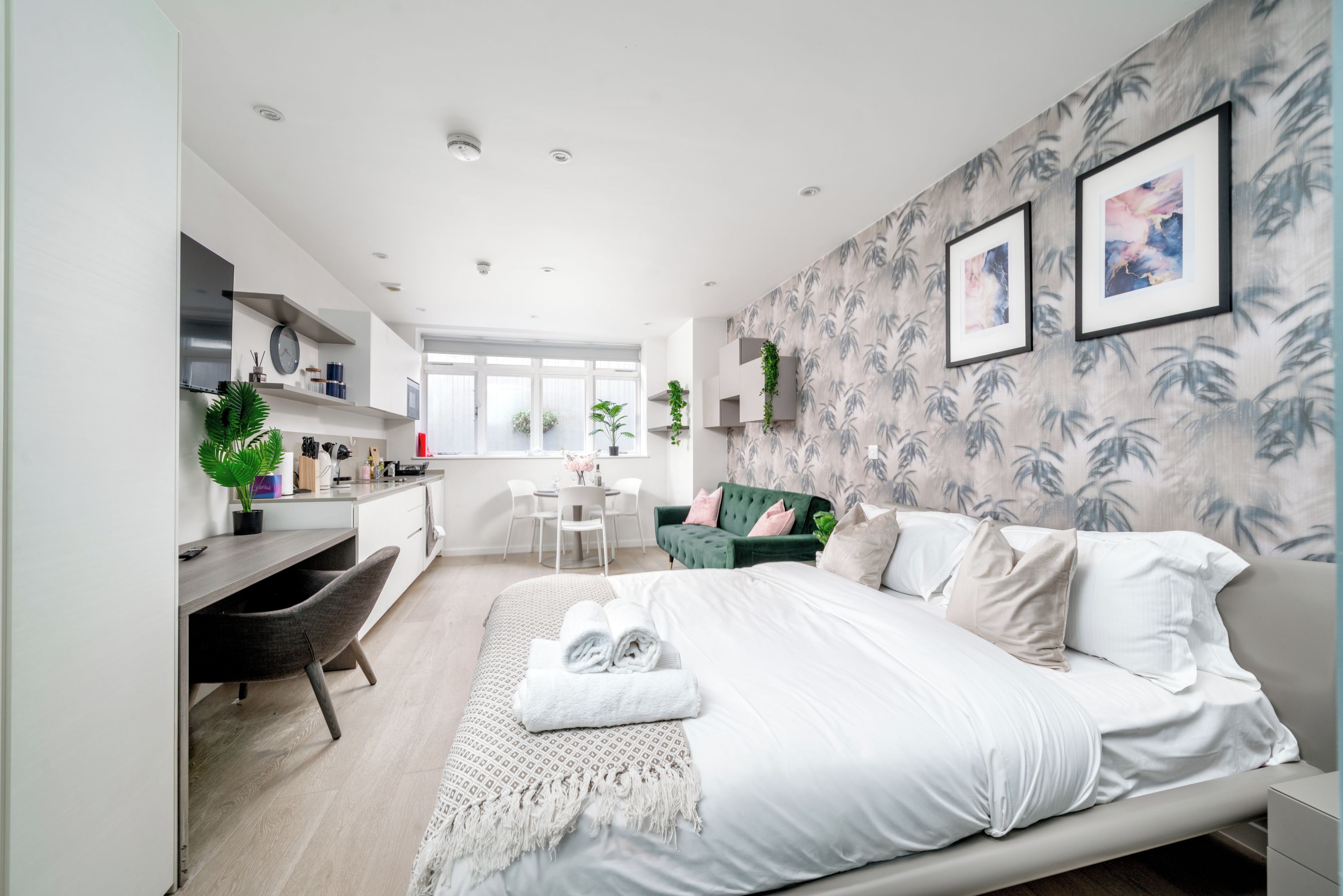 A modern bedroom with a bed, a desk, and a seating area.