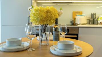 A dining table with a vase of yellow flowers, a bottle of wine, and two glasses.