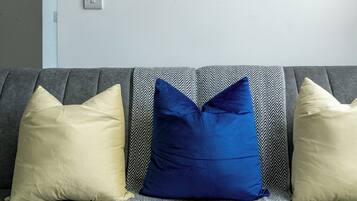 A living room with a grey sofa, two framed pictures on the wall, and a patterned throw.