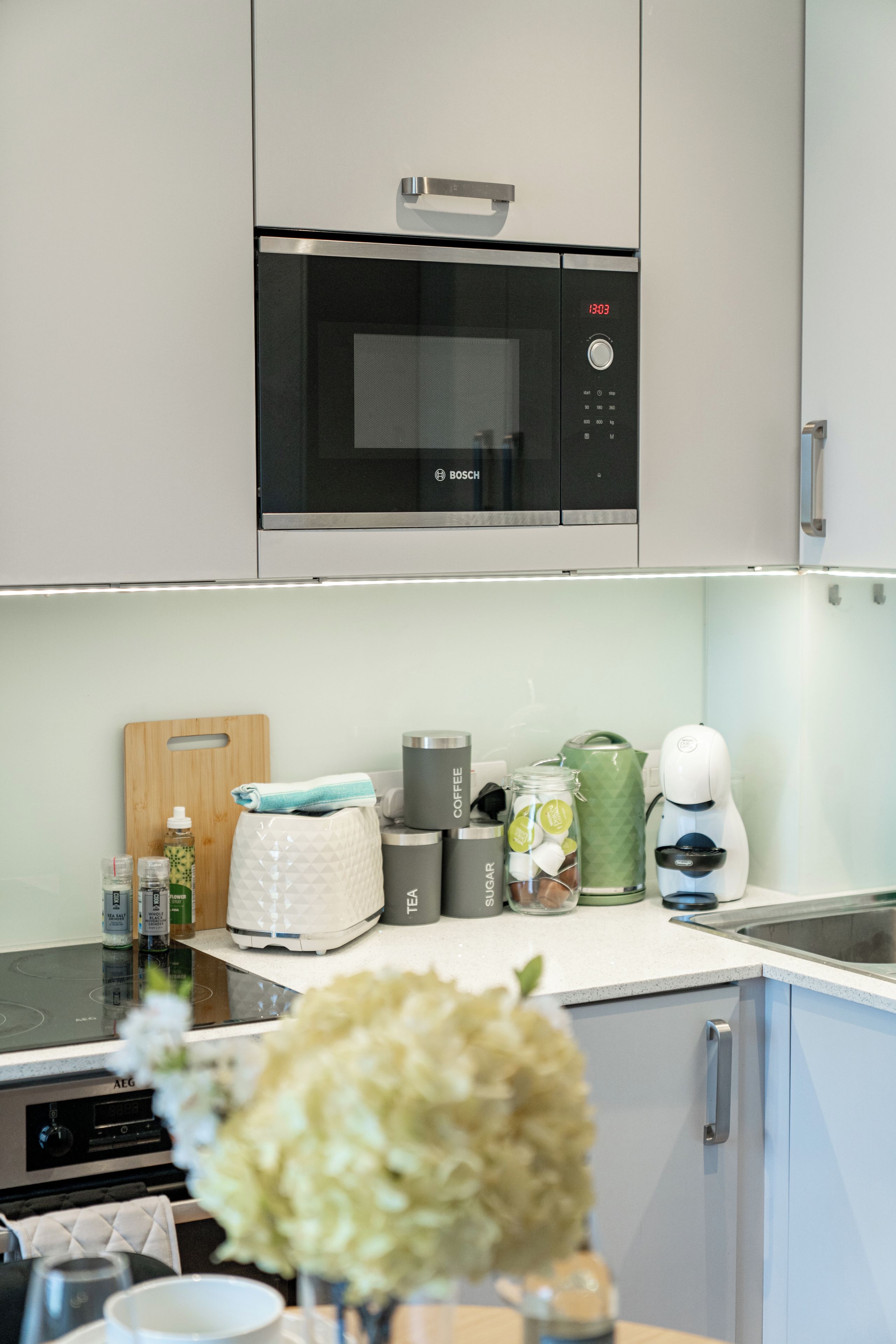 A modern kitchen with a Bosch microwave, a coffee machine, and a kettle on the counter.