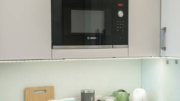 A modern kitchen with a Bosch microwave, a coffee machine, and a kettle on the counter.