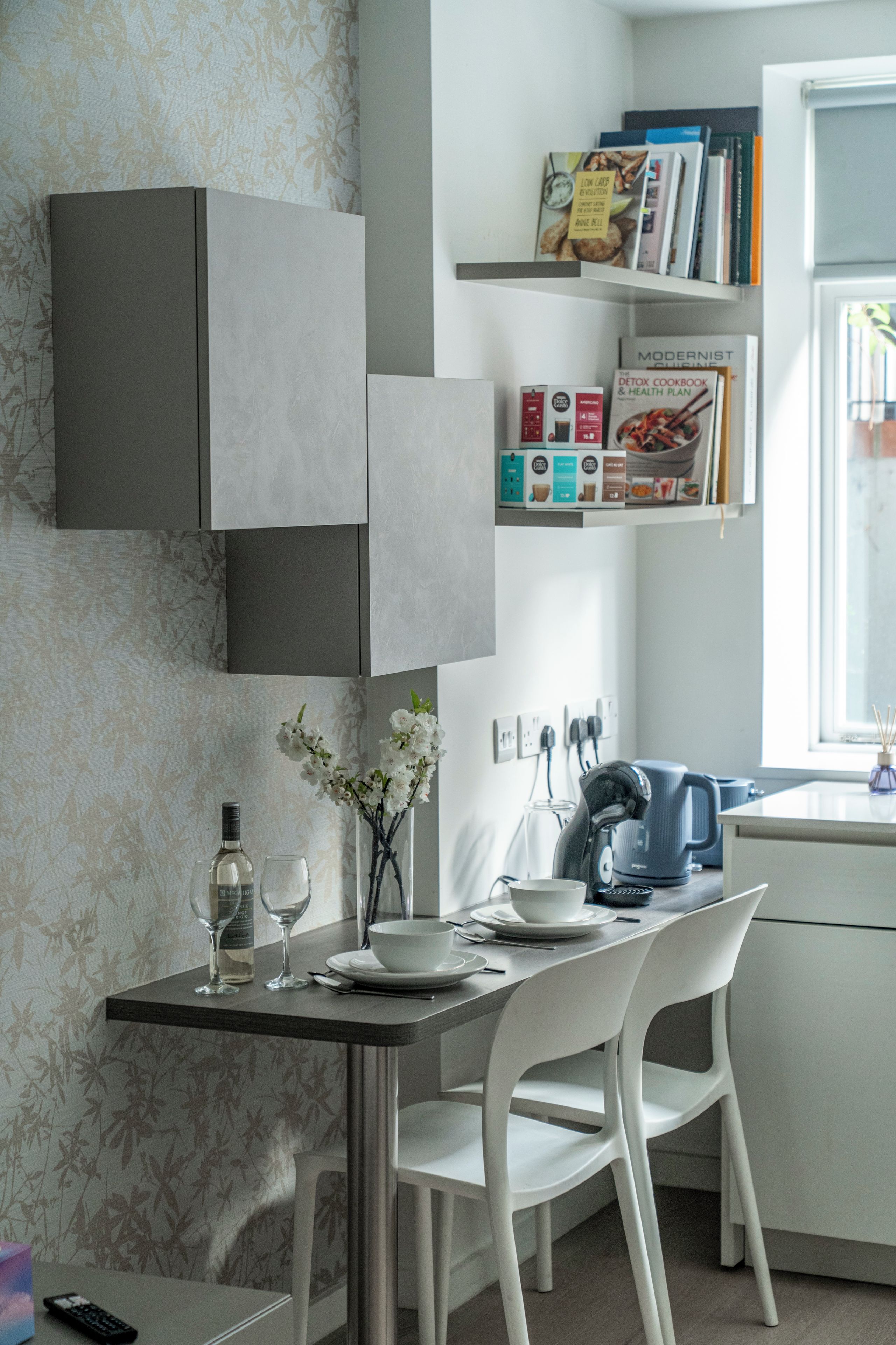 A modern kitchen with white cabinetry, a dining table with chairs, and a window with natural light.