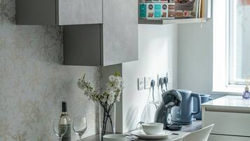A modern kitchen with white cabinetry, a dining table with chairs, and a window with natural light.