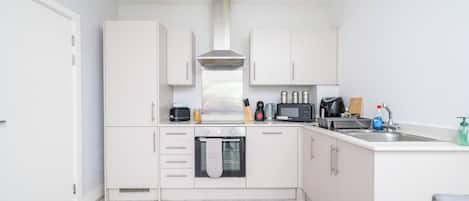 A compact kitchen with white cabinets, a built-in oven, a microwave, and a sink.
