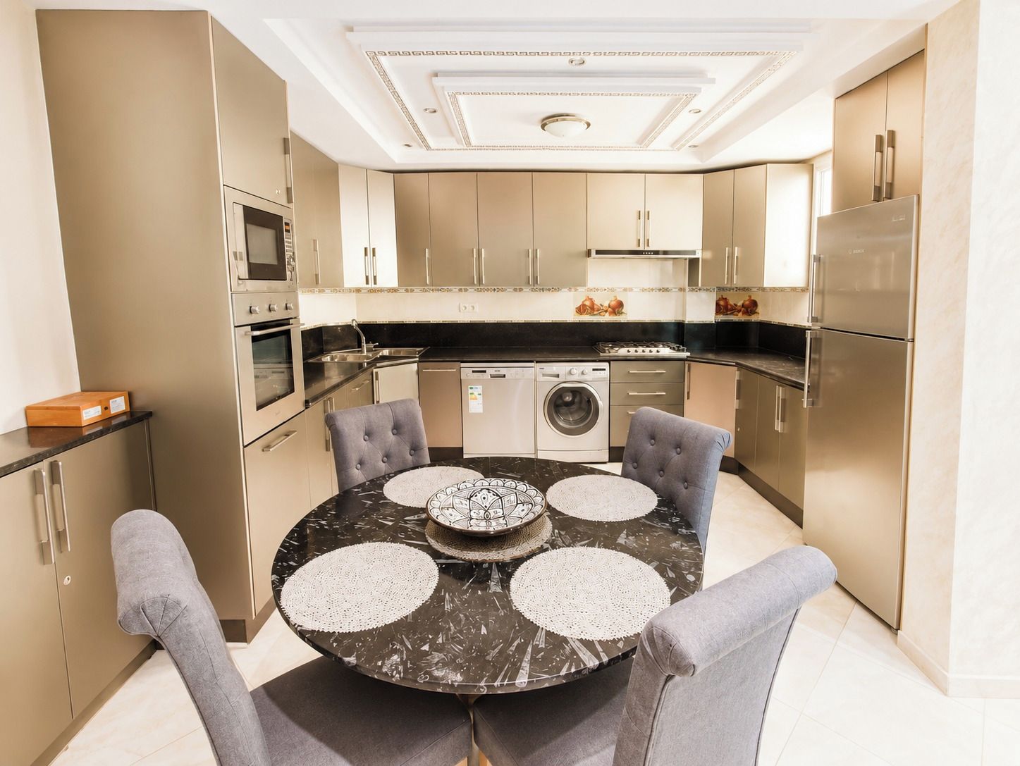 Une cuisine moderne avec une table ronde, quatre chaises et des appareils électroménagers en acier inoxydable.