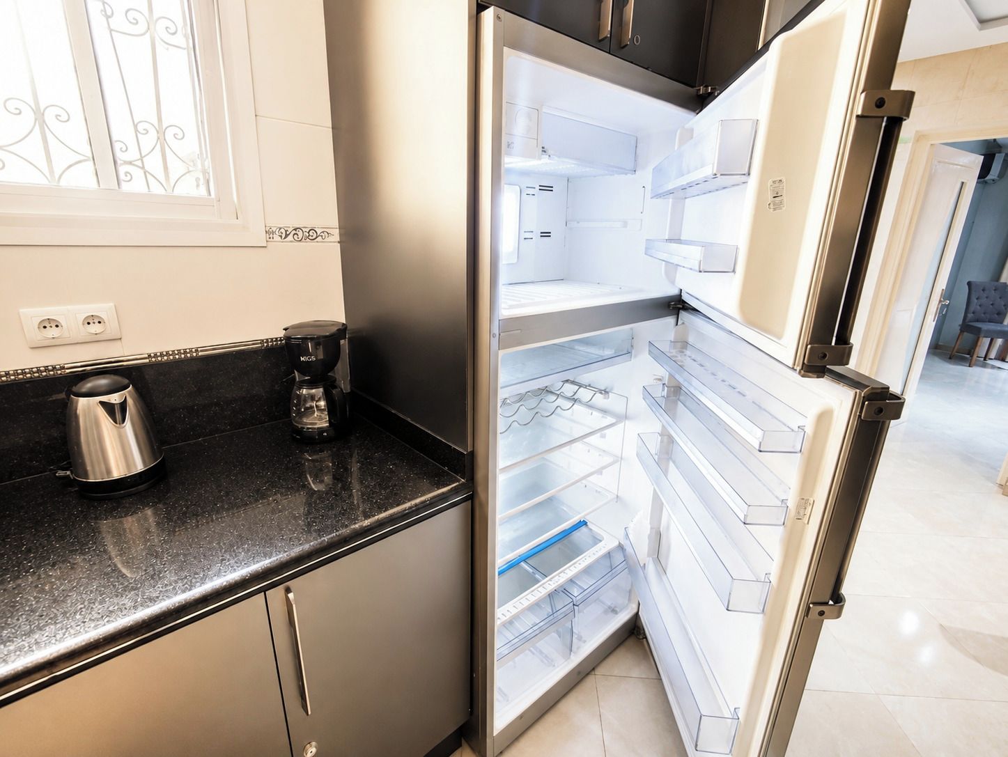 Una cocina moderna con un refrigerador de acero inoxidable, una cafetera y un hervidor sobre la encimera.