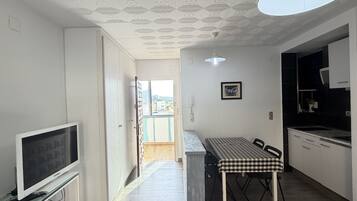 Una cocina moderna con comedor, un televisor sobre un mueble bajo y un techo con diseño geométrico.