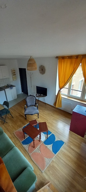 Ett vardagsrum med en soffa, en tv, ett matbord och ett köksområde i bakgrunden.