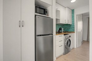 A modern kitchen with a stainless steel refrigerator, microwave, and built-in washing machine. - Oasis Duna_ Srta Pez&Pool with Pool, Private Terrace and Wi-Fi (Corralejo)