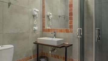 A bathroom with a toilet, sink, mirror, and shower.