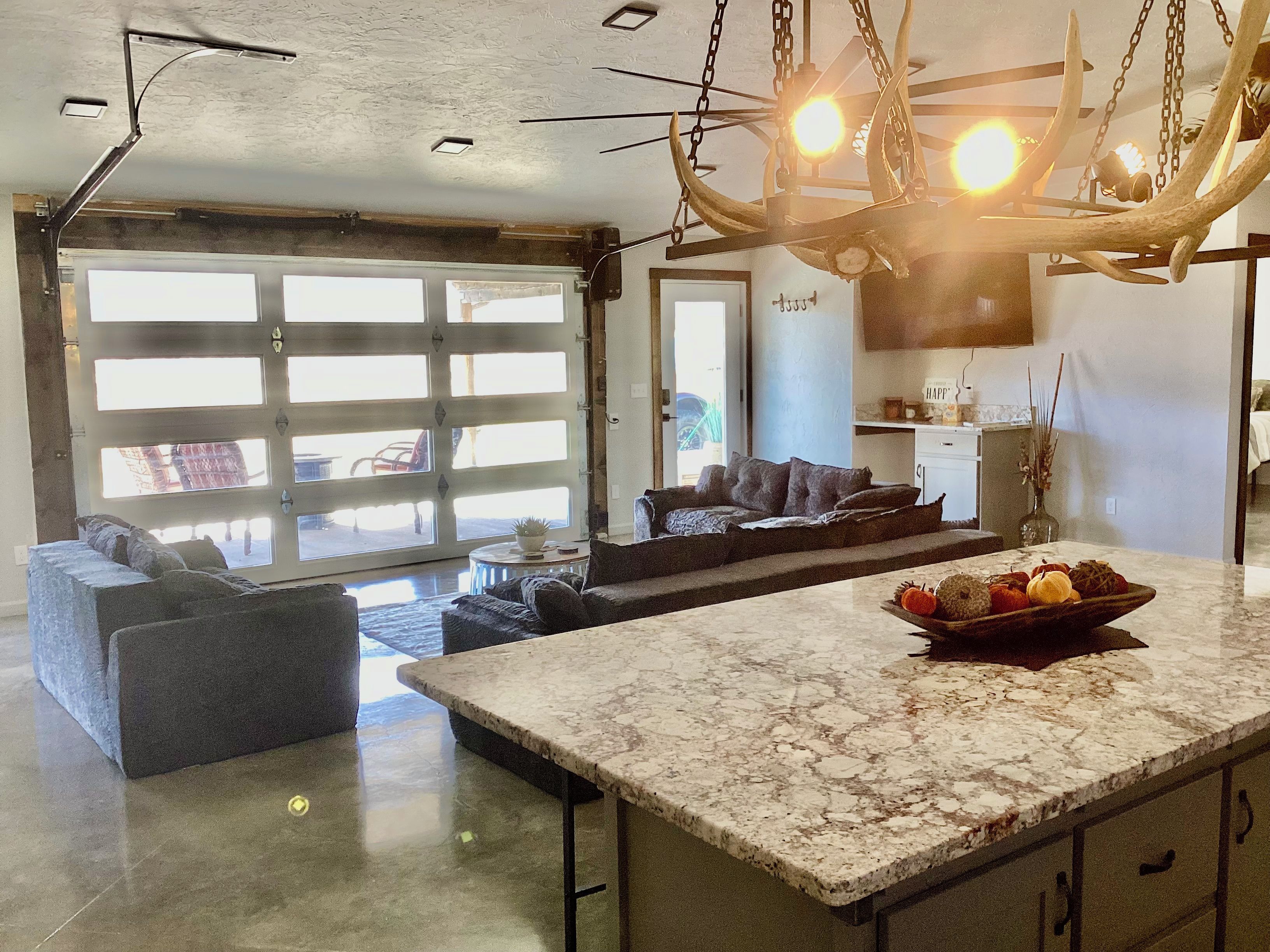 A spacious living area with a large window, a sofa, a coffee table, and a kitchen area with a marble countertop.