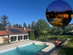 Uma casa com piscina, painéis solares e um jardim.