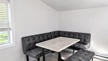 Een hoekappartement met een grijze modulaire bank, een vierkant tafel en een bankje.