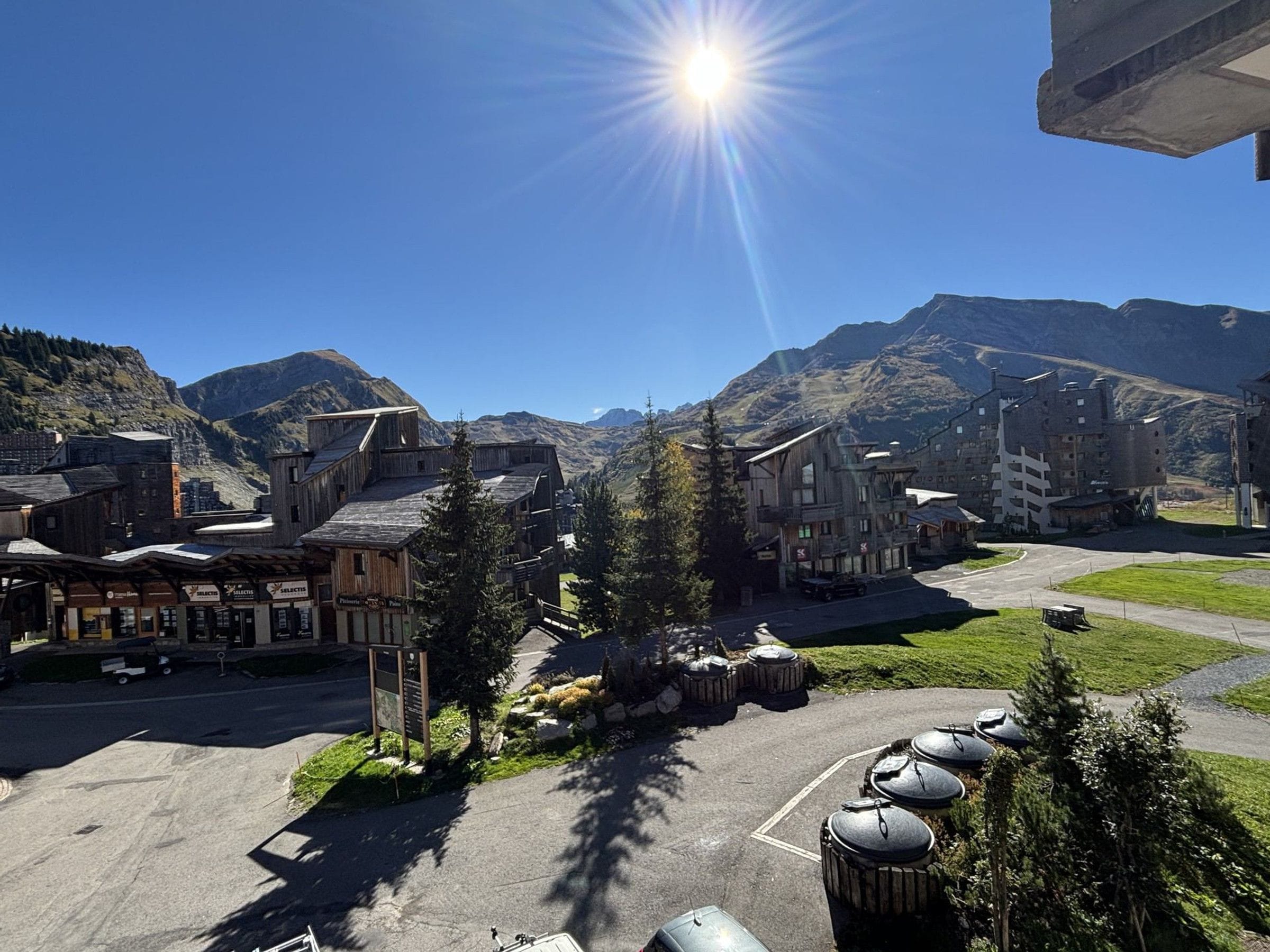 Un pueblo con edificios, una zona de estacionamiento y montañas al fondo.