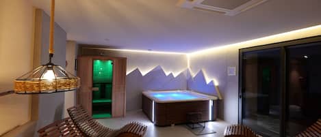 A modern spa room with a hot tub, wooden seating, and a glass partition.